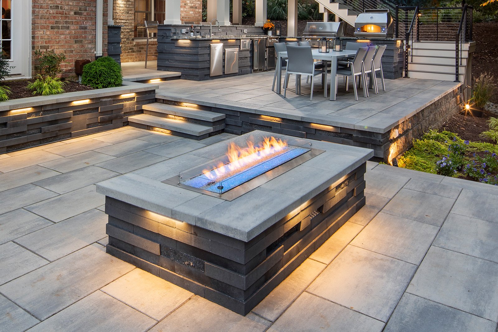 Contemporary fire pit in Great Falls that creates a cozy gathering spot framed by sleek lounge furniture and a custom-built stone seat wall.