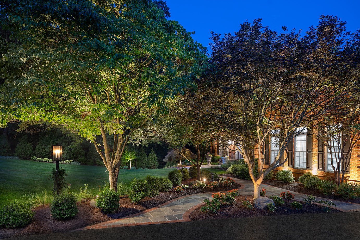 A beautiful landscape lit up with lighting around the walkway. This project was designed and built by Rossen Landscape.